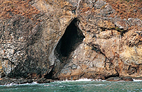 岩石的节理受海浪冲击而扩大，形成沿海崖的洞穴。